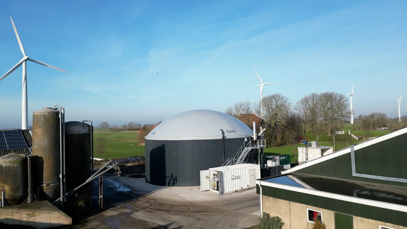 Biolectric digester with wind turbines in the background