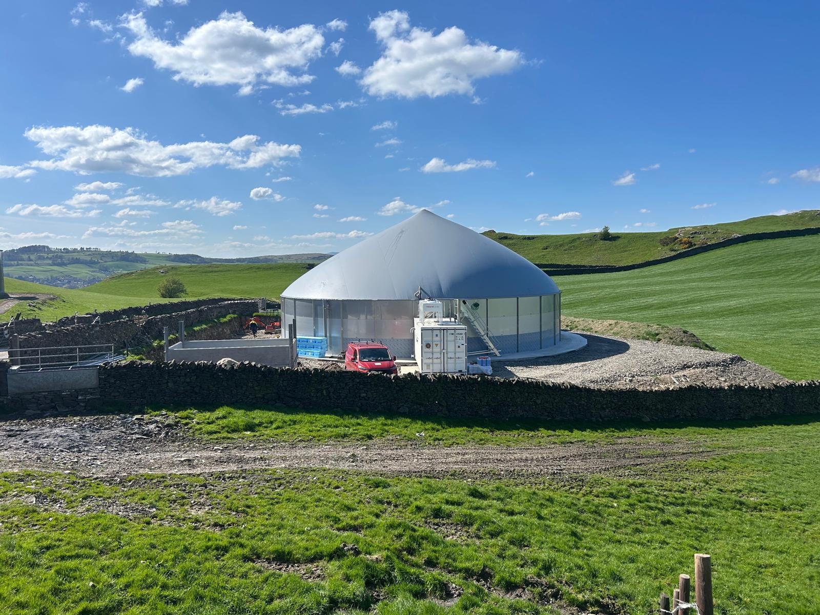 A completed anaerobic digestion installation on a working farm, digester dome and equipment container in place