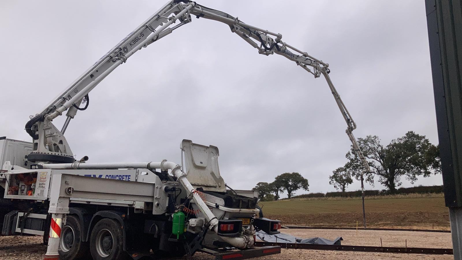 A concrete pump extending its boom to pour a digester base